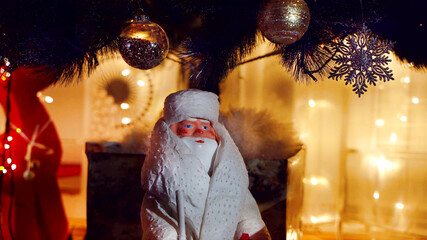Santa Claus is standing under the Christmas tree among the gifts on the background of Christmas...