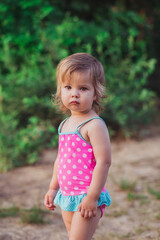 Charming baby in swimsuit by the river 