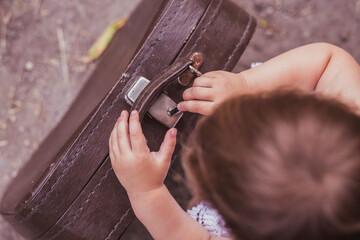 Adorable baby trying to open a suitcase with a hair clip
