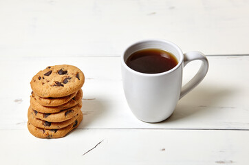 White cup with coffee and traditional cookies on a white wooden background, closeup. Tasty breakfast, morning routine concept