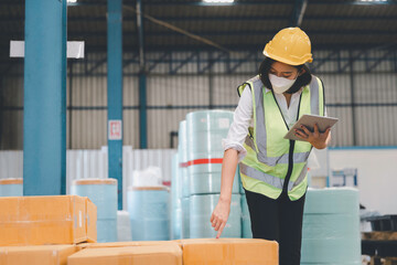 Factory woman staff in medical face mask and protective safety using digital tablet working checking inventory storage at textile warehouse
