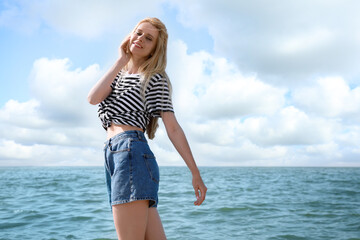 Fototapeta na wymiar Beautiful young woman near sea on sunny day in summer