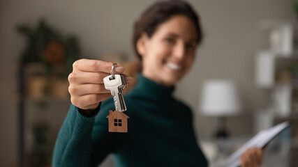 Close up focus on keys, smiling woman realtor selling apartment, offering to client, showing at camera, holding documents, contract, making purchasing deal, real estate agent, mortgage or rent - obrazy, fototapety, plakaty