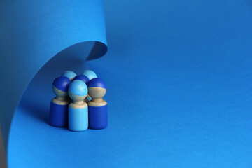 group of five blue wooden toy people are covered with a blue sheet of paper, blue background with copy space - obrazy, fototapety, plakaty