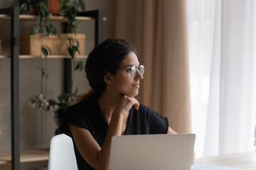 Close up thoughtful woman in glasses pondering project, touching chin, looking to aside, distracted...