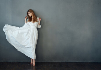 Fototapeta na wymiar pretty woman dancing in a white dress on a dark background