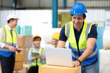 engineer or factory worker using laptop computer and talking to someone