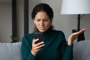 Close up angry dissatisfied woman looking at phone screen, unhappy confused young female having...