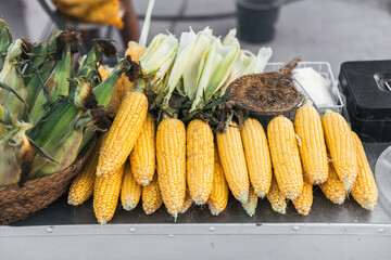 A pile of fresh raw corncobs on the table at a street food stall