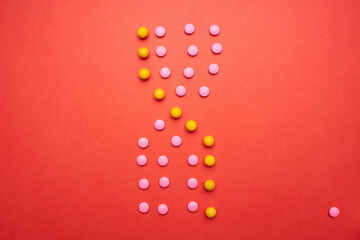 multicolored pills on red background top view health pharmaceuticals