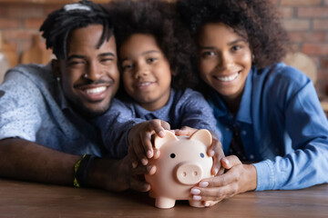 Close up blurred portrait of smiling young African American family with daughter recommend saving...