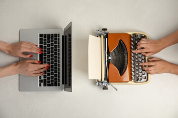 Women using laptop and old typewriter at light table, top view. Concept of technology progress