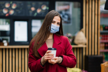 Close up portrait of a caucasian female wearing a medical mask and standing in the street and cafe