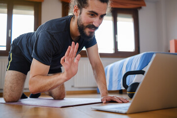 Personal trainer greeting participants during an online exercise class at home