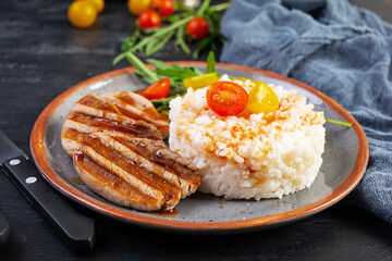 Rice with grilled pork meat, tomatoes and green herbs on dark background