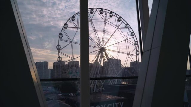 A beautiful Ferris wheel rotates against the background of the sunset sky. Shooting in motion
