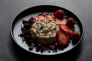 DELICIOUS HEALTHY COOKED OATS FRESH SUMMER FRUIT & SEEDS ON DARK PLATE 