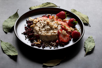 HEALTHY BREAKFAST COOKED PORRIDGE OATS FRESH FRUIT BAY LEAVES RUSTIC TABLE DECORATION 