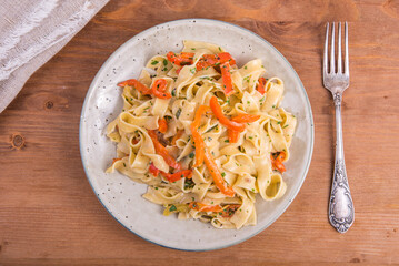 Italian fettuccine pasta with pepper, basil and cream sauce, portion in a plate, top view.