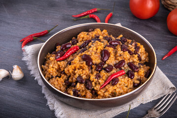 Mexican rice with tomato and beans, serving in a plate with hot chili peppers on the table with peppers and tomatoes, ingredients for cooking.