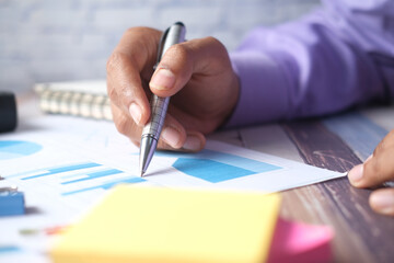 man hand with pen analyzing bar chart on paper 