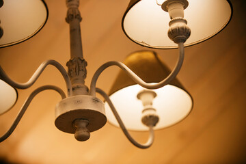 Bright lamps with fabric shades are lit on an elegant and beautiful chandelier in the evening,...