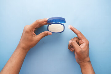 top view of man hand using petroleum jelly on blue background 