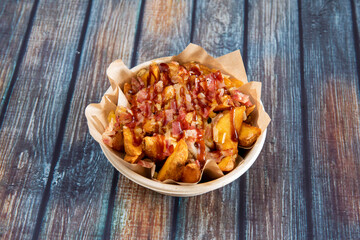 Popular recipe for potato wedges fried in their own skin with lots of fried bacon chopped into tacos and plenty of barbacoa sauce cooked in a home delivery restaurant