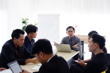 Senior Asian successful manager man is meeting and brainstorming with businesspeople staff and teamwork about business of marketing and stock market in meeting room at office