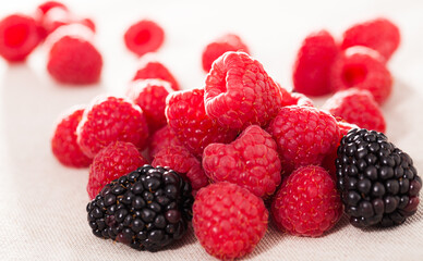 handful of fresh raspberry and blackberry berries on white background