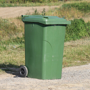 a big green wheeled bin stands at a countryroad in the dutch countryside in zeeland in springtime