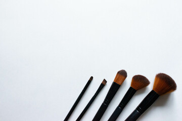 Brushes a flat lay with copy space. Beauty cosmetic makeup product layout. Stylish design. Creative fashionable concept. Cosmetics make-up brushes collection on a white background, top view.
