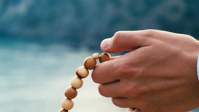 Wooden rosary in male hands, close-up