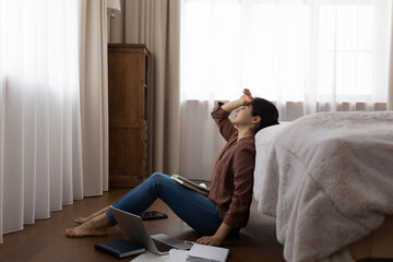 Unhappy tired young Indian female student distressed with homework prepare for exam on computer at home. Upset ethnic woman exhausted studying online on laptop with textbooks. Deadline concept.