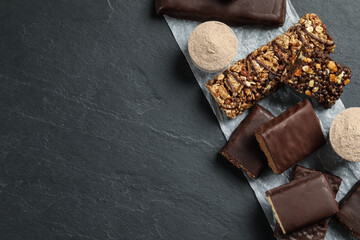 Different tasty energy bars and protein powder on black table, flat lay. Space for text
