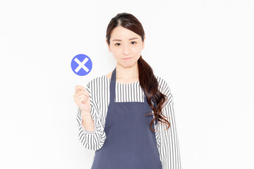 NGのプラカードを持っているエプロン姿の女性