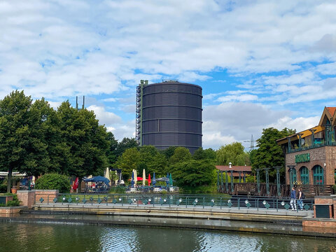 Oberhausen (Centro), Germany - July 9. 2021: View over water canal beyond beach on gasometer tower against summer sky
