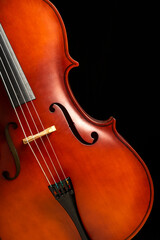 FRONT VIEW OF A TILTED CELLO ON DARK BACKGROUND. COPY SPACE. CLASSICAL MUSIC ORCHESTRA CONCERT.