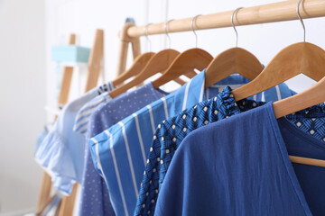 Rack with stylish hanging clothes in dressing room