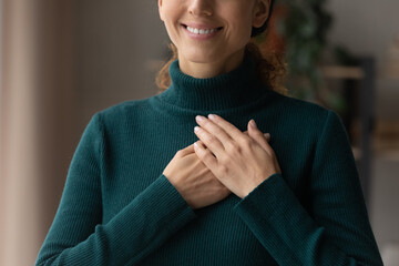 Cropped close up smiling grateful woman holding folded hands on chest, thankful young female expressing gratitude, thanking god and faith, feeling love, making wish, charity and support concept - obrazy, fototapety, plakaty