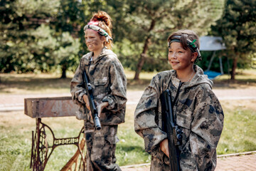 Boy and girl with a weapon in their hands playing laser tag shooting game in outdoor. War...