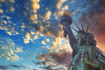 Fototapeta premium Dramatic view of the Statue of Liberty, with Manhattan in a red sunset background