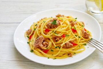  Healthy and easy Italian Traditional Dish"Spaghetti with tuna",spaghetti with tuna in olive oil,parsley,garlics,salt and peppers on plate with white wood table background.Copy space