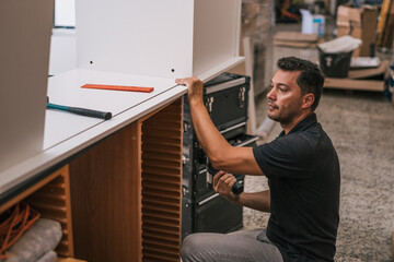 Man using a drill to put together two pieces of furniture in a workshop