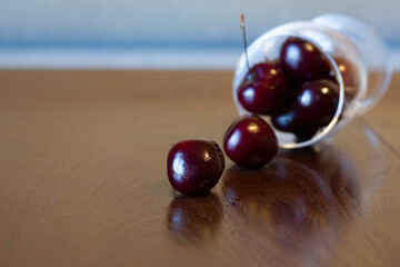 A large ripe beautiful cherry fell out of a transparent glass