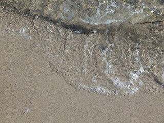 Background with washed up sea water on the beach, copy space below