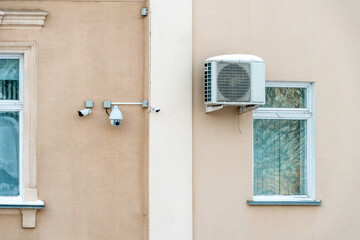 An outdoor air conditioner unit installed on the wall of a residential building next to the window. Installation, repair and maintenance of air conditioning systems in residential premises.
