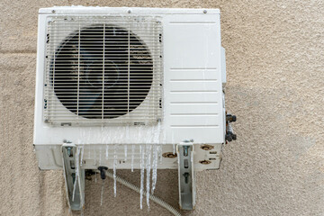 An outdoor air conditioner unit installed on the outer wall of a residential building close-up....