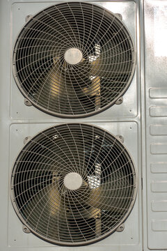 An outdoor air conditioner unit consisting of two fans. A large industrial air conditioner on the wall of a store or enterprise. Repair and maintenance of the air conditioning system