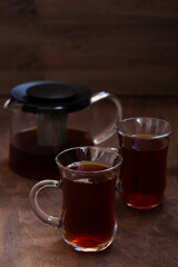 Turkish tea in traditional glass on the wooden table close-up. two glass cups of black tea with teapot on the dark brown background with copy space. vertical